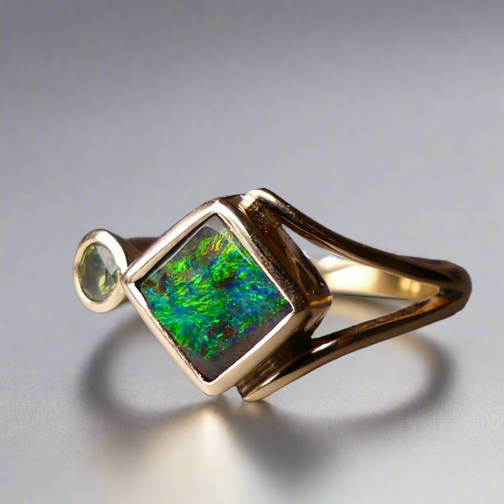 Discover the elegance of this unique 9k gold Australian Boulder Opal ring, beautifully paired with a stunning Australian sapphire. The vibrant opal’s natural patterns and the sapphire’s green blue hues create a captivating contrast, making this ring a true statement piece.
