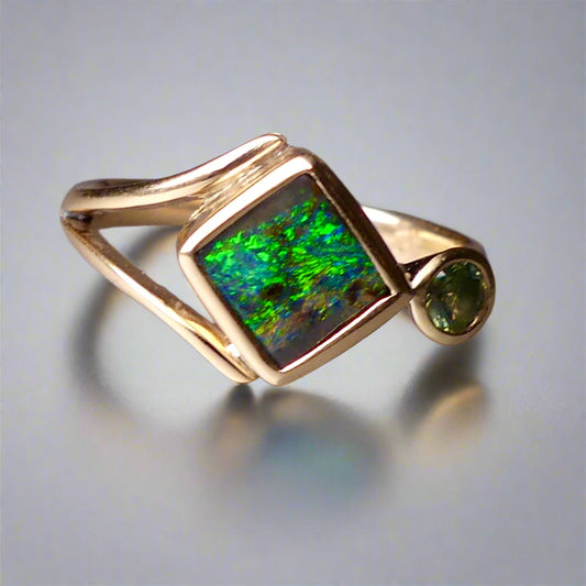 Discover the elegance of this unique 9k gold Australian Boulder Opal ring, beautifully paired with a stunning Australian sapphire. The vibrant opal’s natural patterns and the sapphire’s green blue hues create a captivating contrast, making this ring a true statement piece.