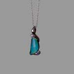 Necklace with a pendant featuring a blue gemstone on a gray background