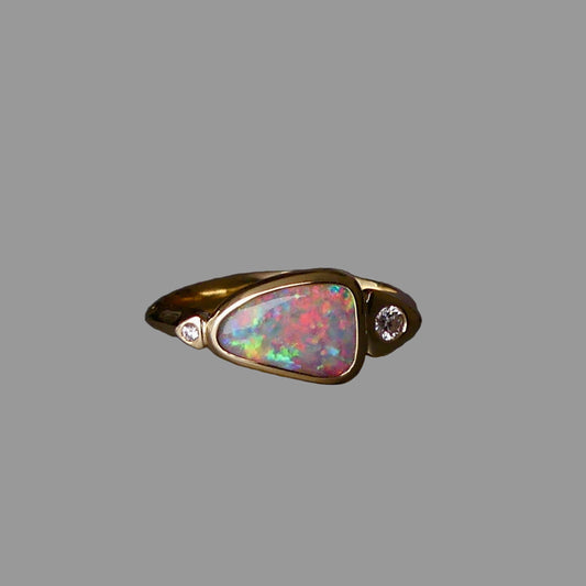 Gold ring with a colorful opal stone and small diamonds on a dark background