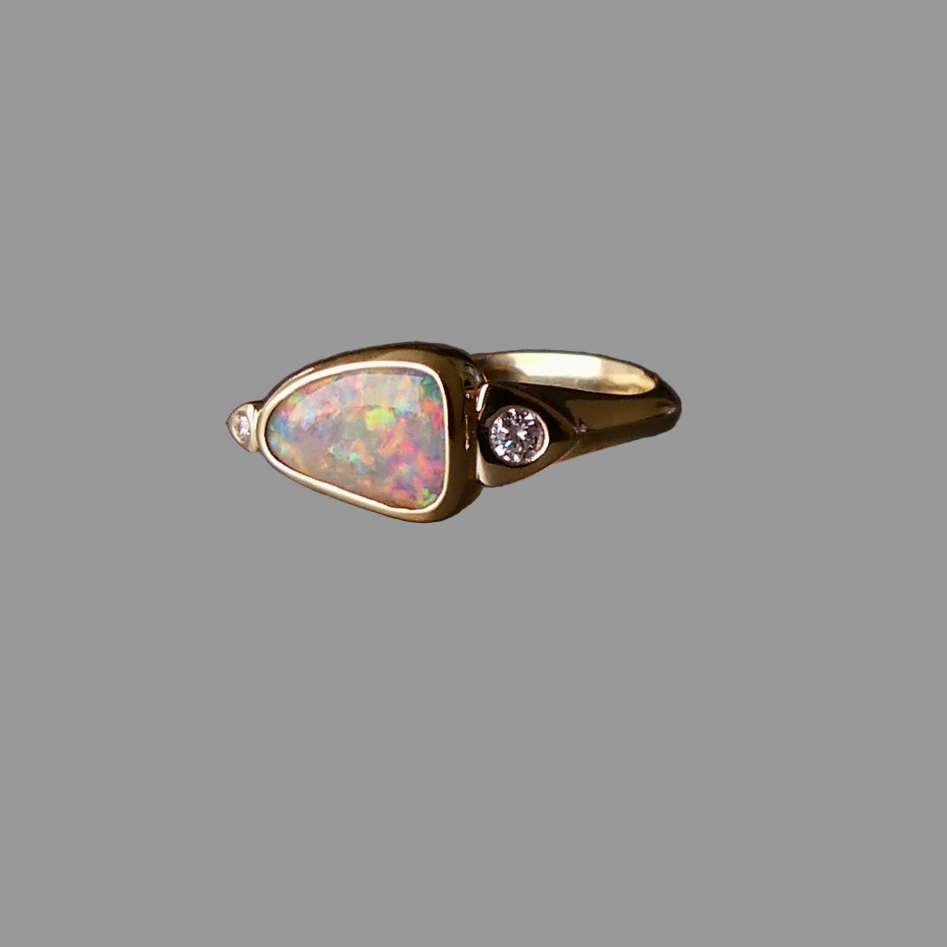 Gold ring with opal stone and diamond on a dark background