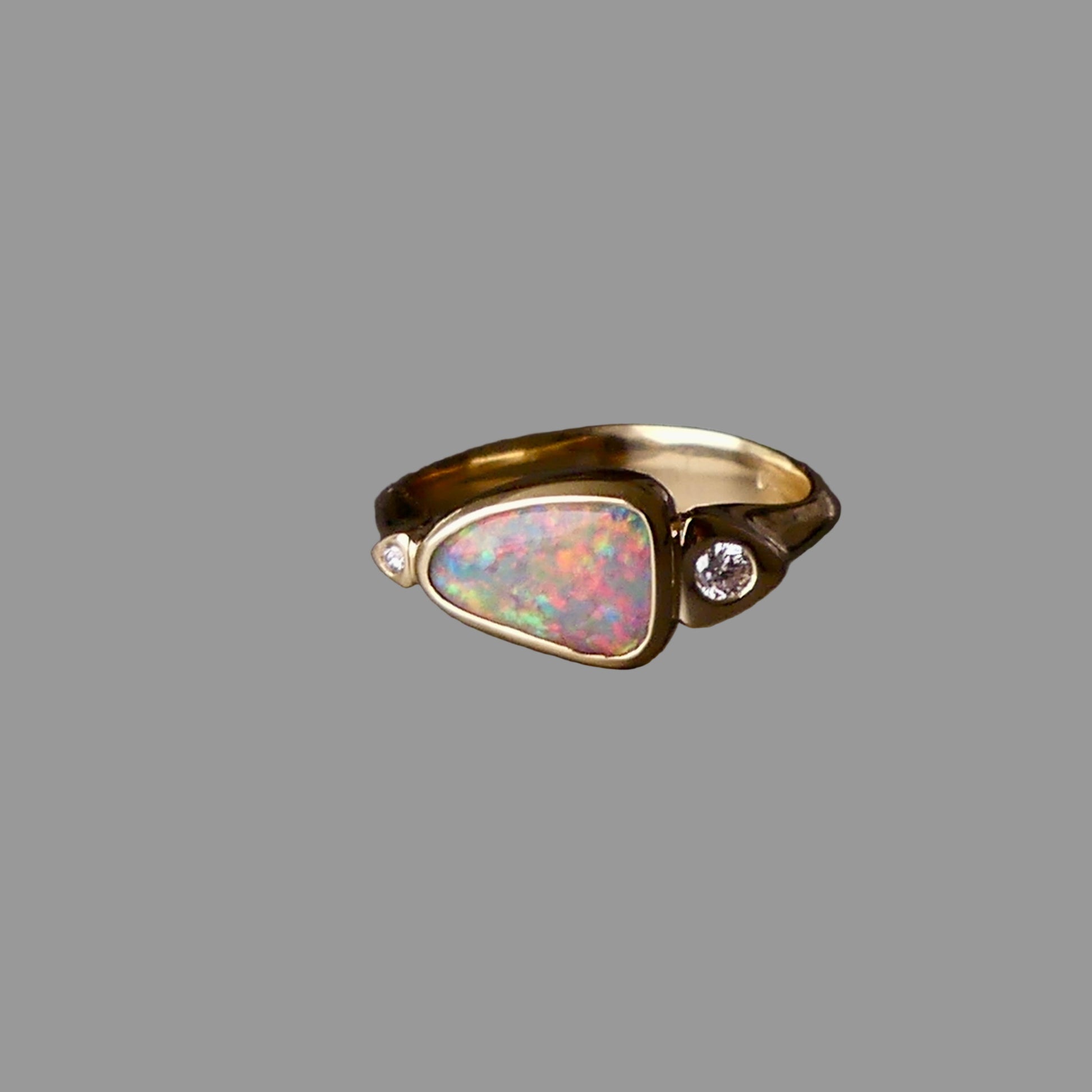 Gold ring with an opal stone and diamonds on a dark background