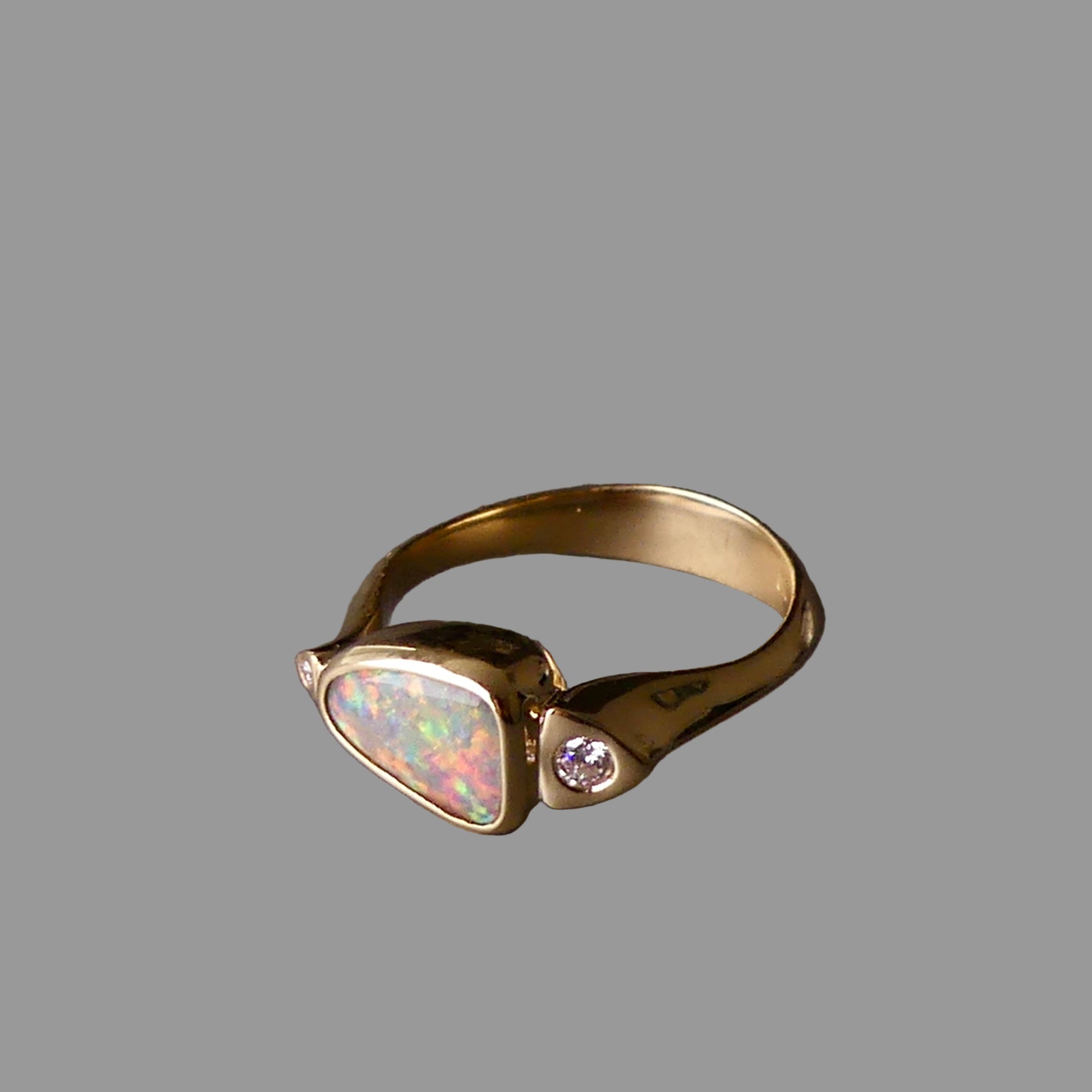 Gold ring with opal and diamond on a dark gray background