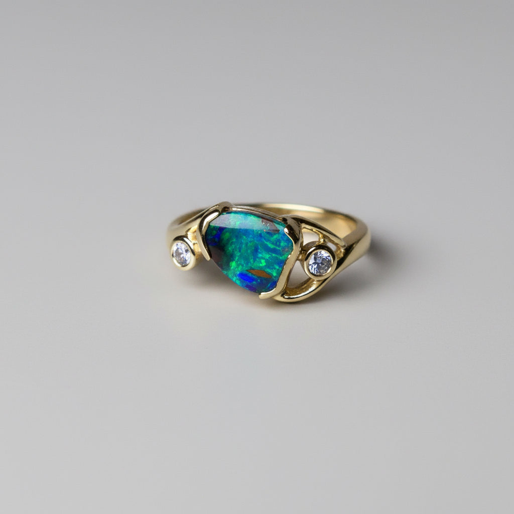 Gold ring with a colorful gemstone on a gray background