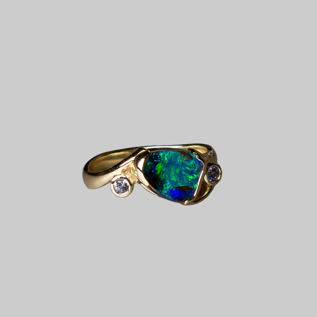 Gold ring with a blue gemstone on a gray background