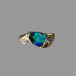Gold ring with a colorful gemstone and small diamonds on a gray background