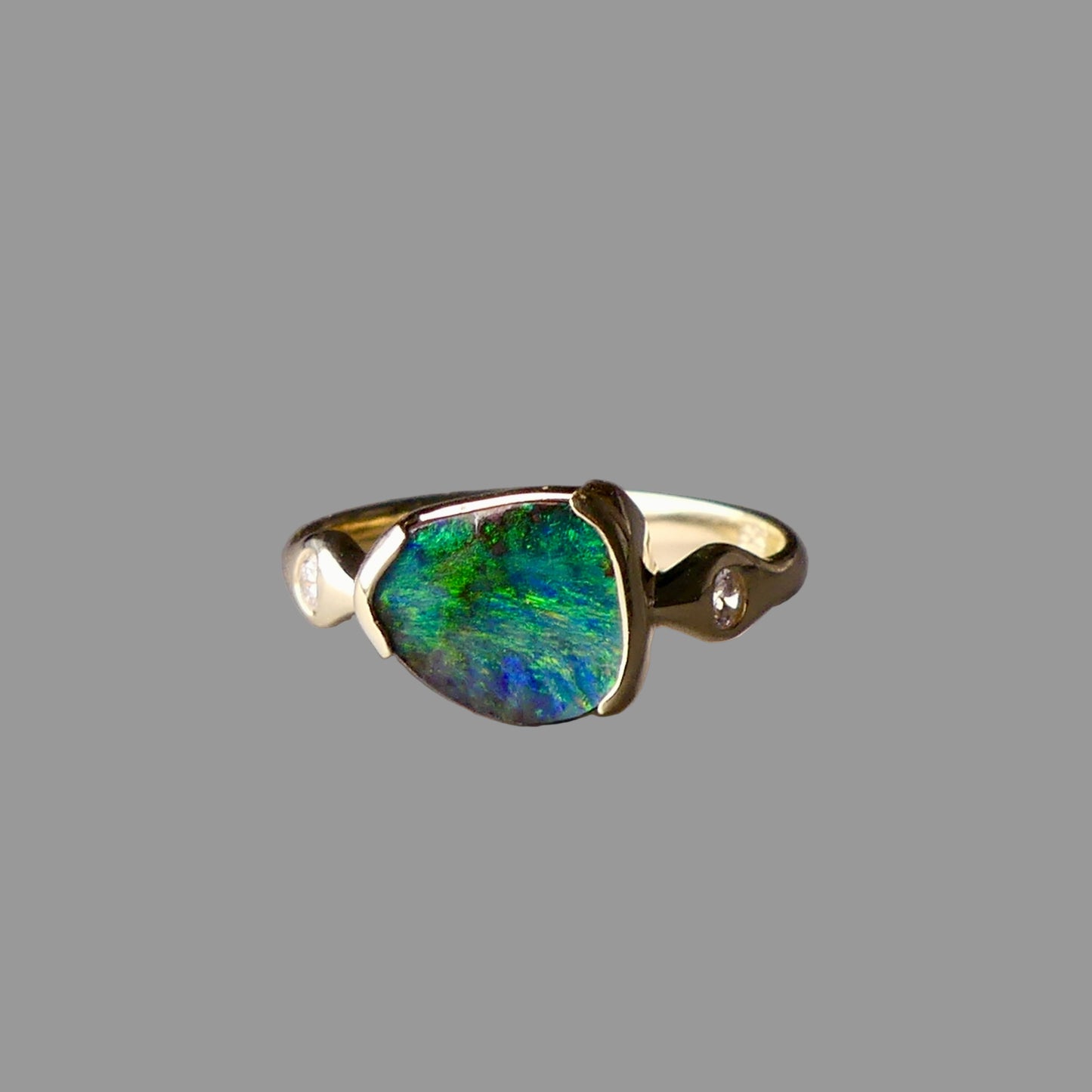 Gold ring with a green gemstone on a gray background