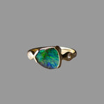 Gold ring with a green gemstone on a gray background