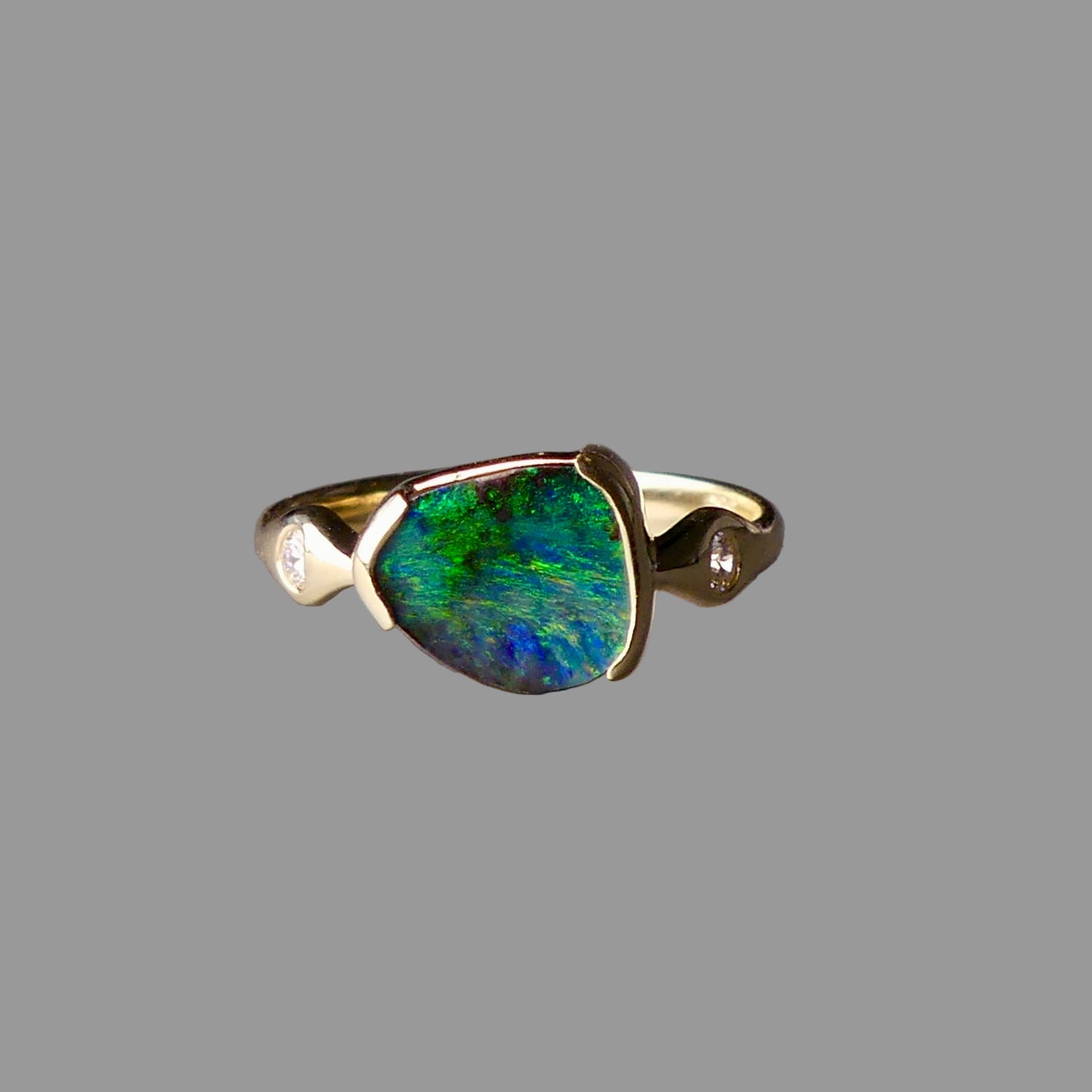 Ring with a green gemstone and gold band on a gray background