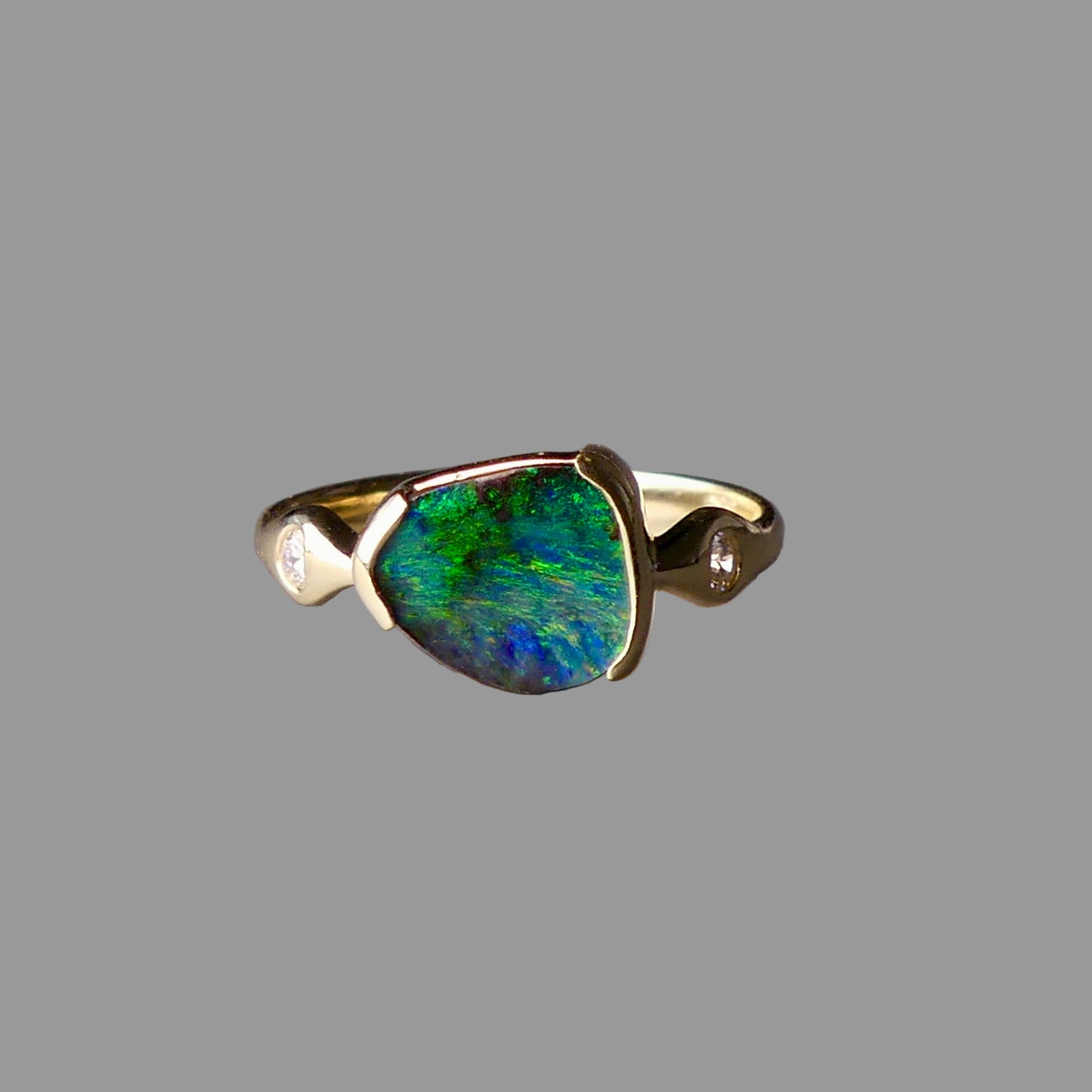 Ring with a green gemstone and gold band on a gray background