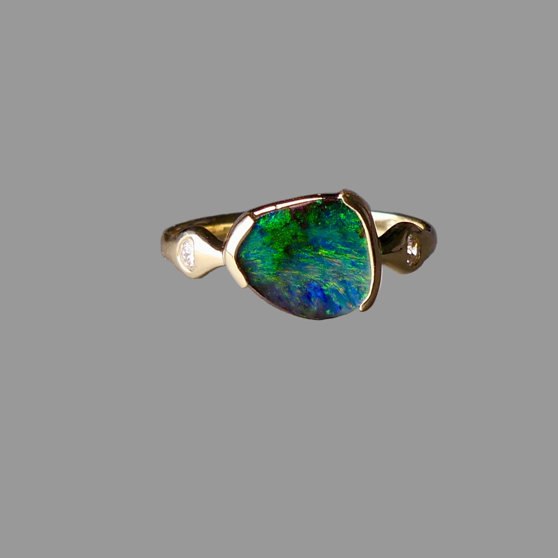 Gold ring with a green and blue gemstone on a gray background