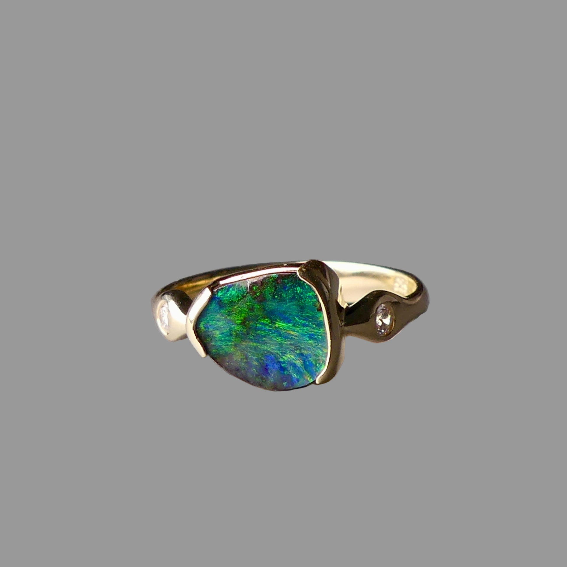 Gold ring with a green gemstone on a gray background