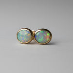 Pair of opal stud earrings on a dark gray background