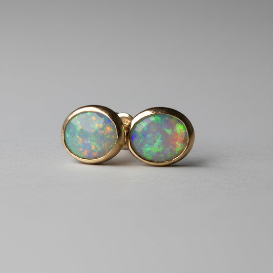 Pair of opal stud earrings on a dark gray background