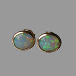 Pair of opal earrings with gold settings on a dark background