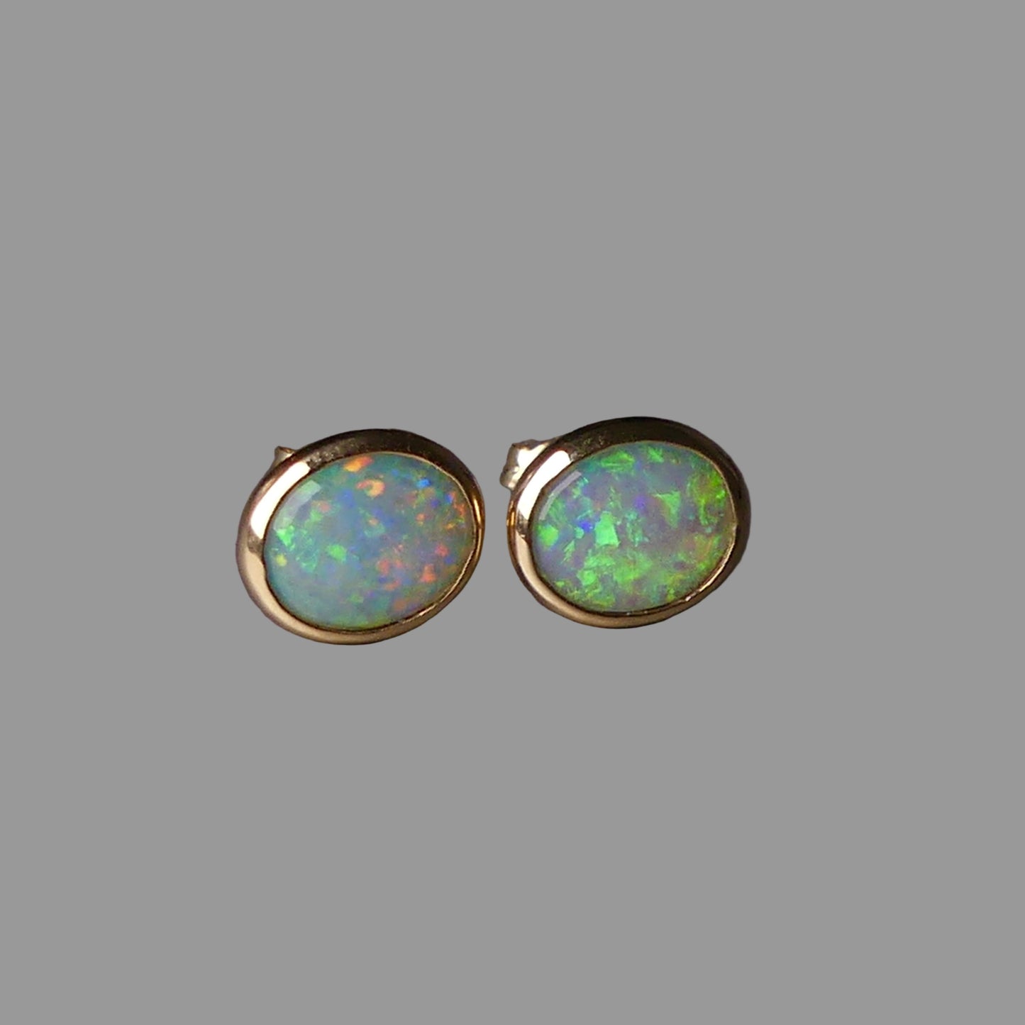 Pair of opal stud earrings on a dark gray background
