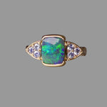Gold ring with an opal stone and diamond accents on a gray background