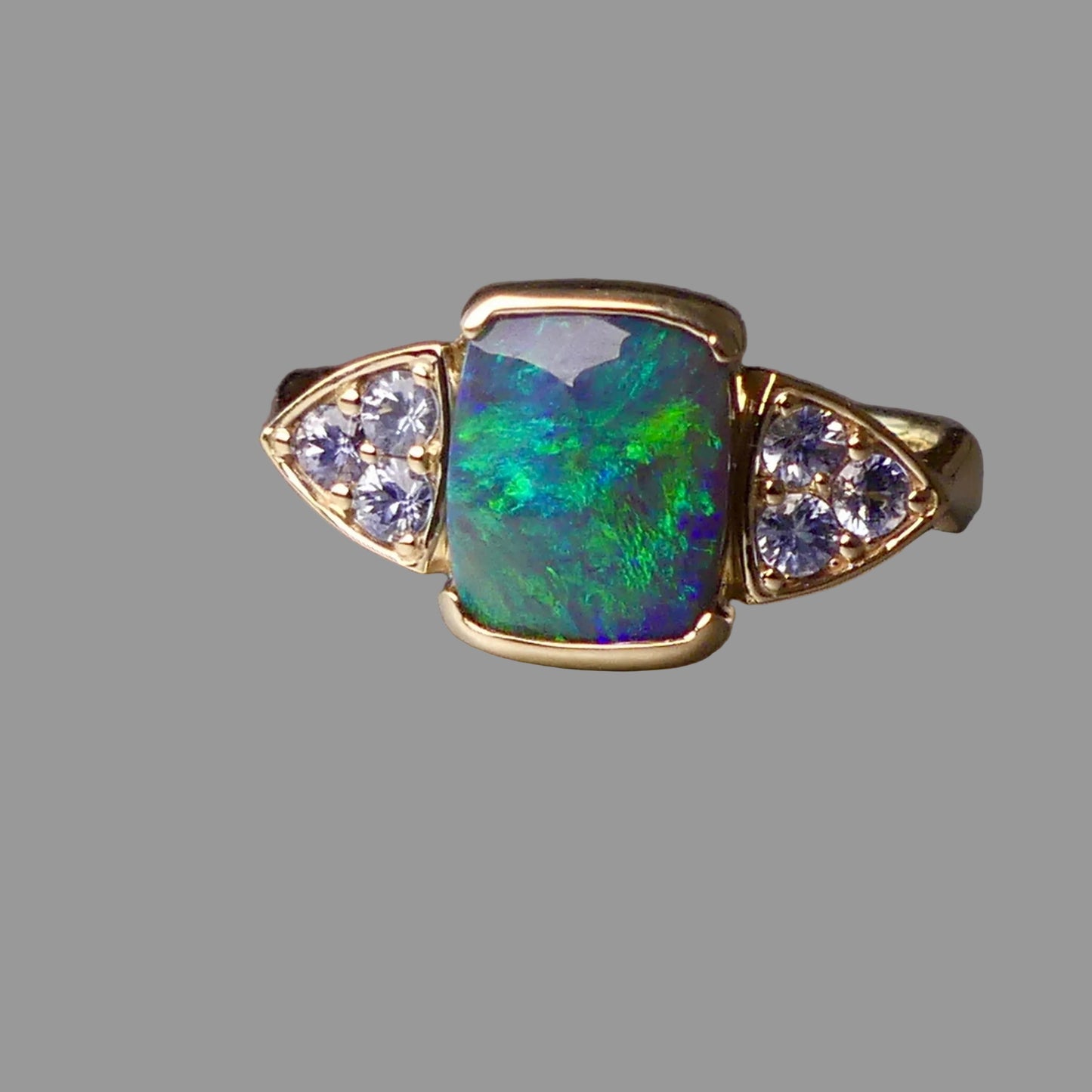 Ring with opal stone and diamond accents on a gray background