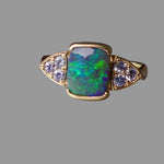 Ring with opal stone and diamond accents on a gray background