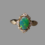 Gold ring with a green opal stone and small diamonds on a gray background