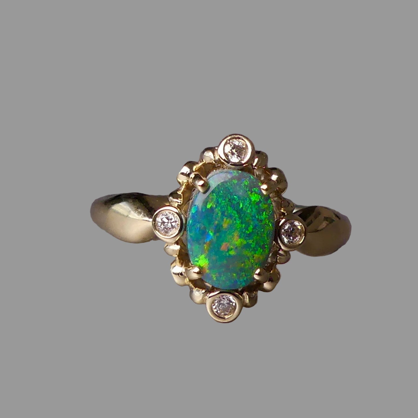 Gold ring with a green opal stone and small diamonds on a gray background