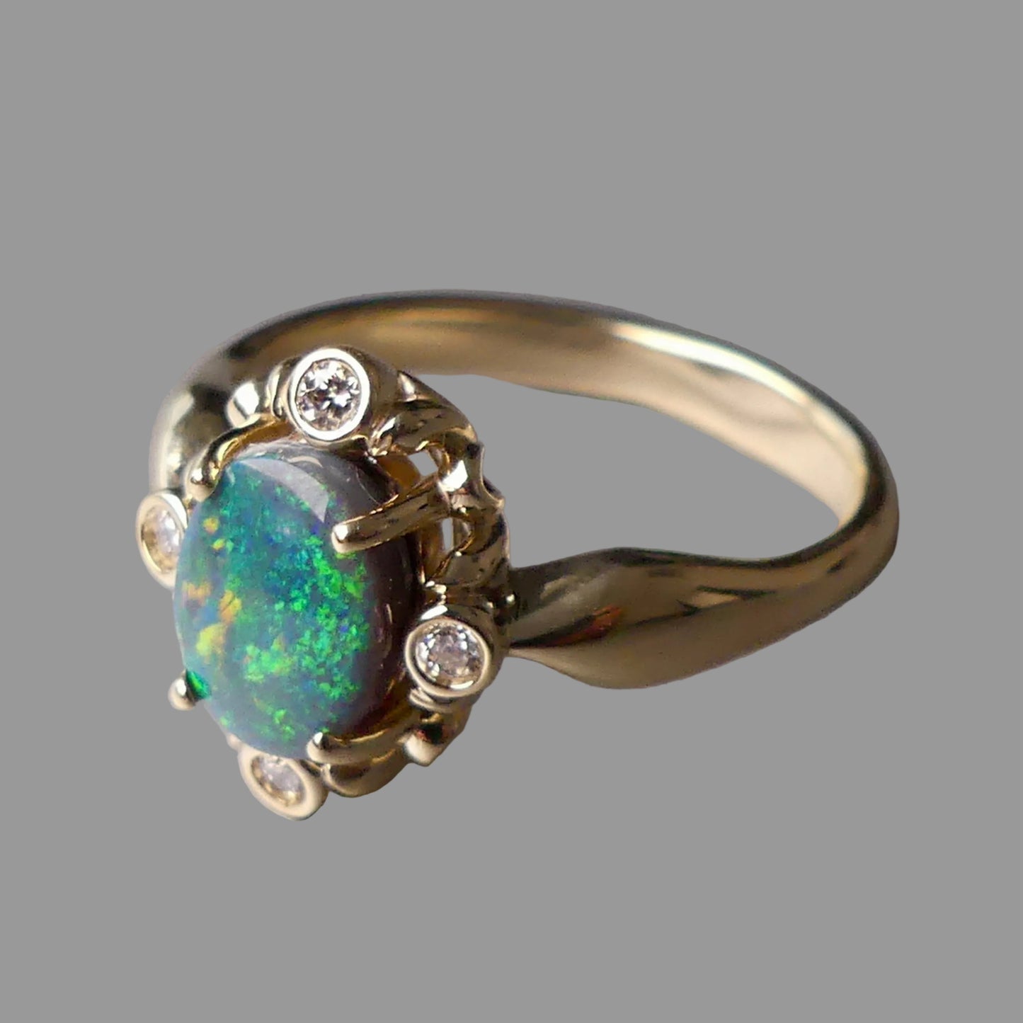 Gold ring with an opal stone and small diamonds on a gray background