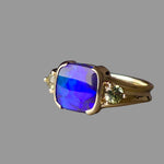 Gold ring with a blue gemstone on a gray background