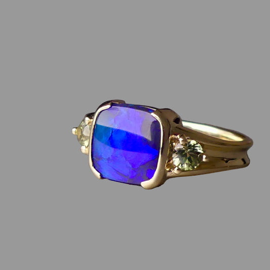 Gold ring with a blue gemstone on a gray background