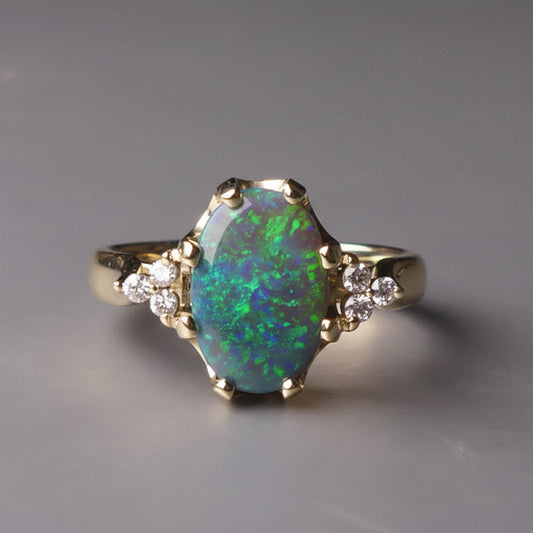 Gold ring with a colorful gemstone on a gray background