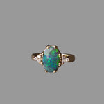 Gold ring with a green opal stone on a gray background