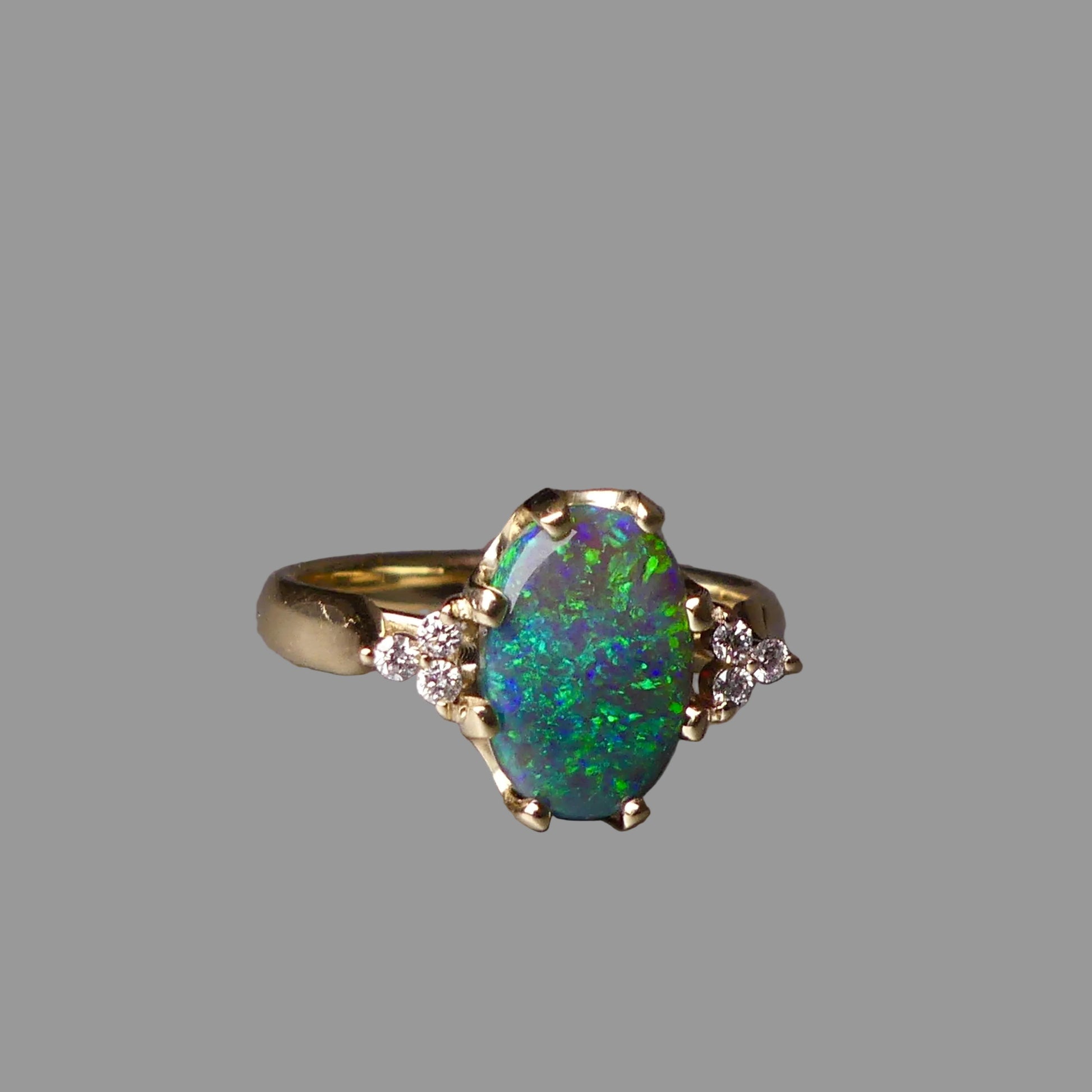 Gold ring with a green opal stone on a gray background