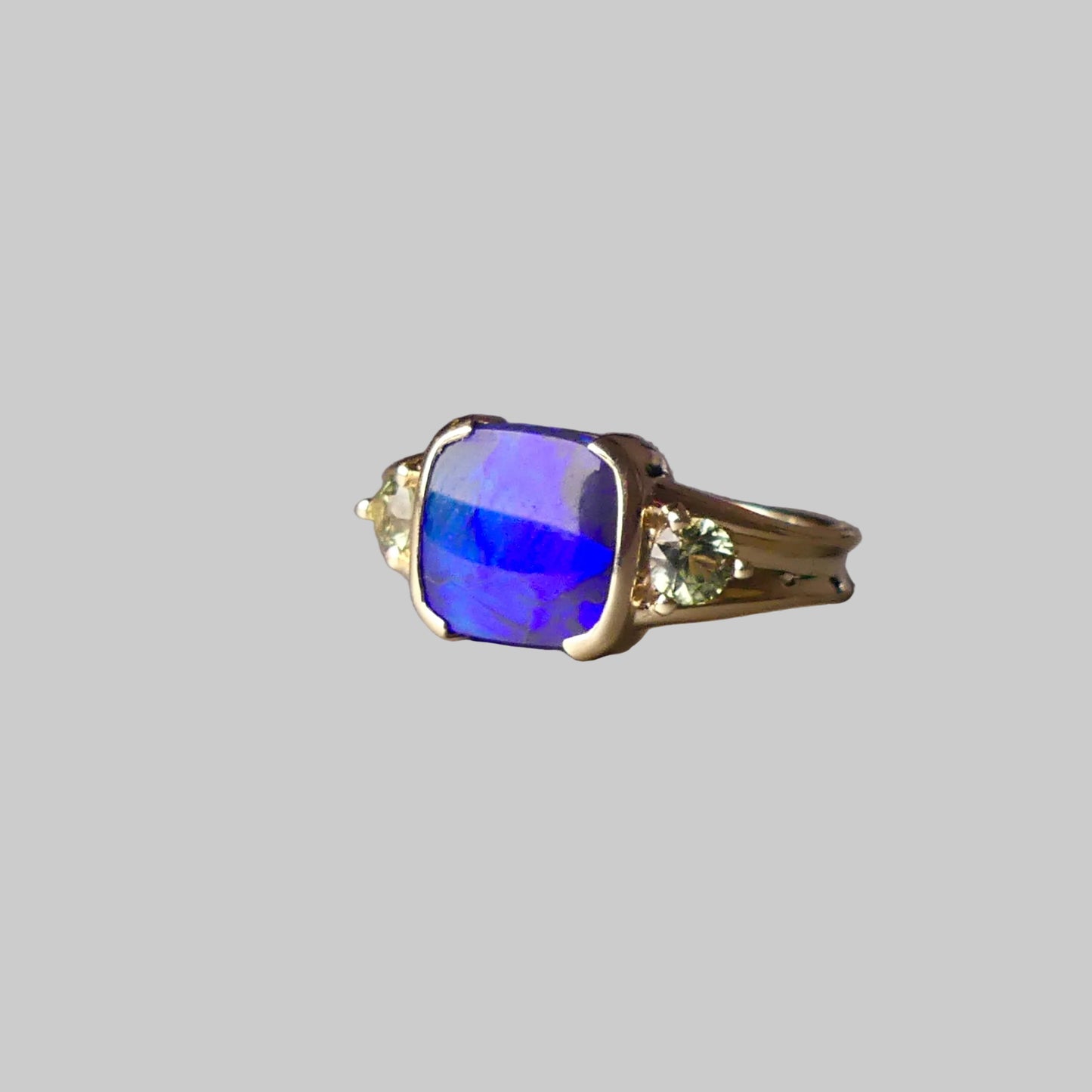 Gold ring with a blue gemstone on a gray surface
