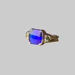 Gold ring with a blue gemstone on a gray surface