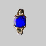 Ring with a blue gemstone and gold accents on a gray background