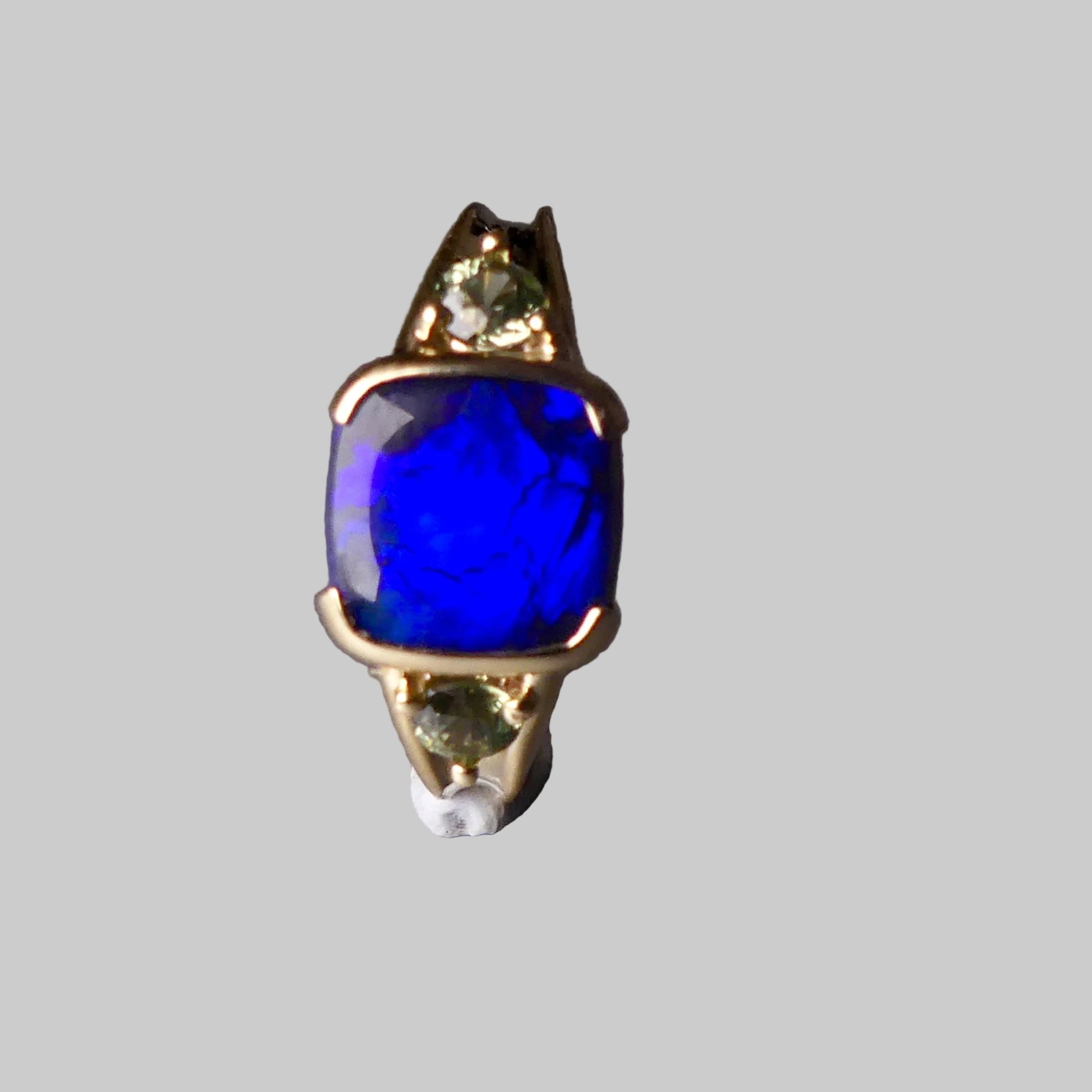 Ring with a blue gemstone and gold accents on a gray background