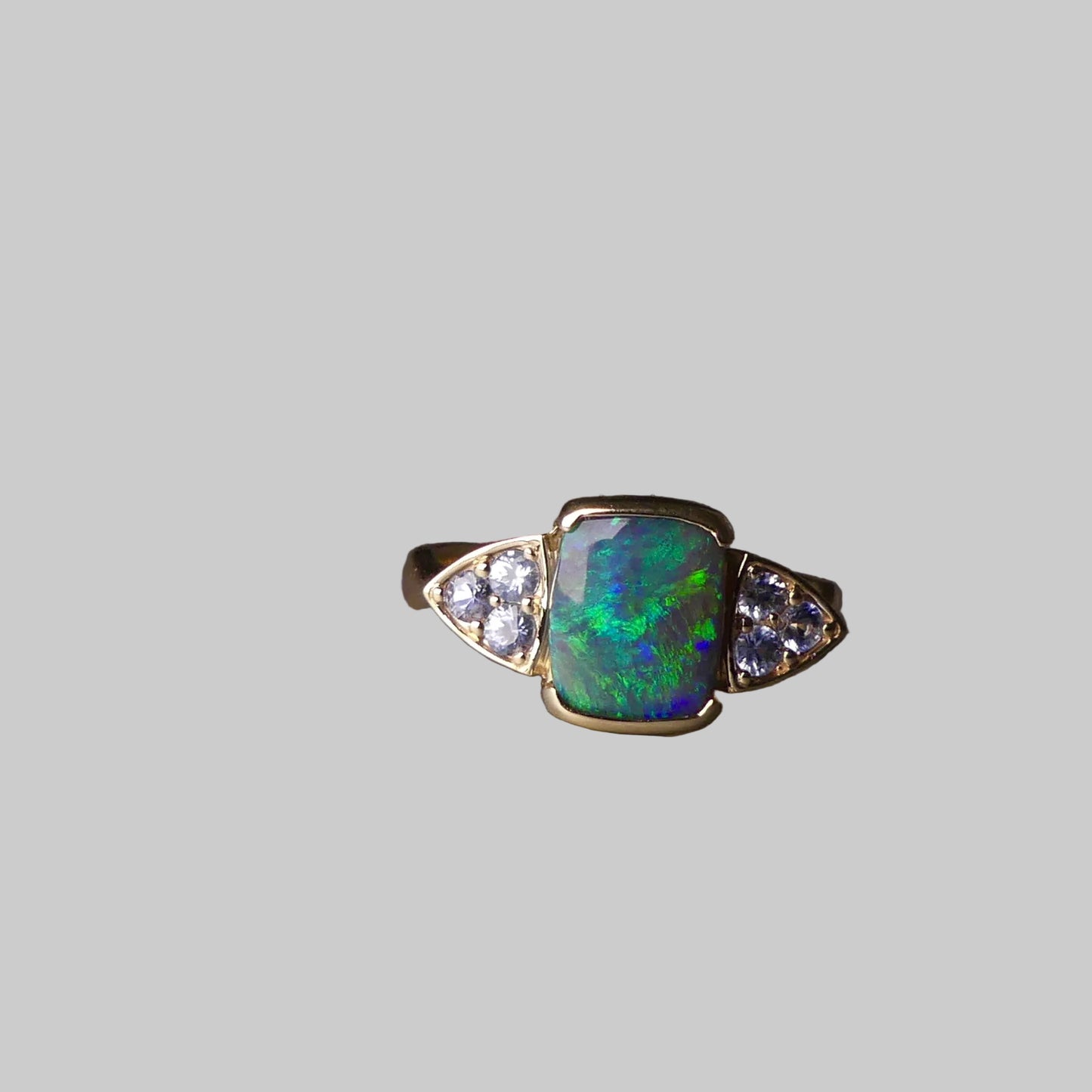 Ring with a green opal stone and diamond accents on a gray surface