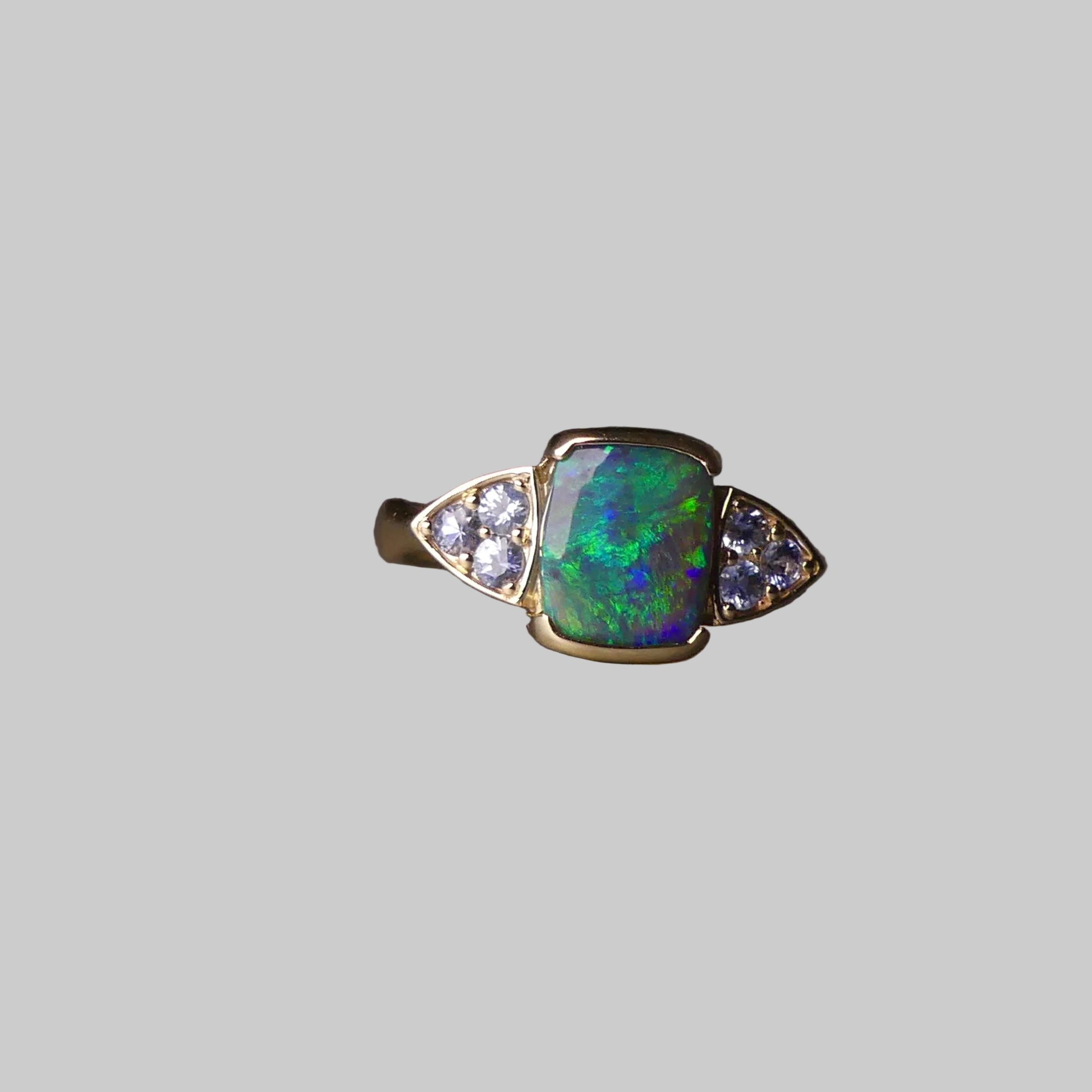 Ring with a green gemstone and small diamonds on a dark surface