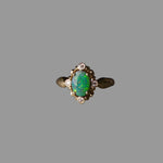 Gold ring with a green gemstone on a dark surface