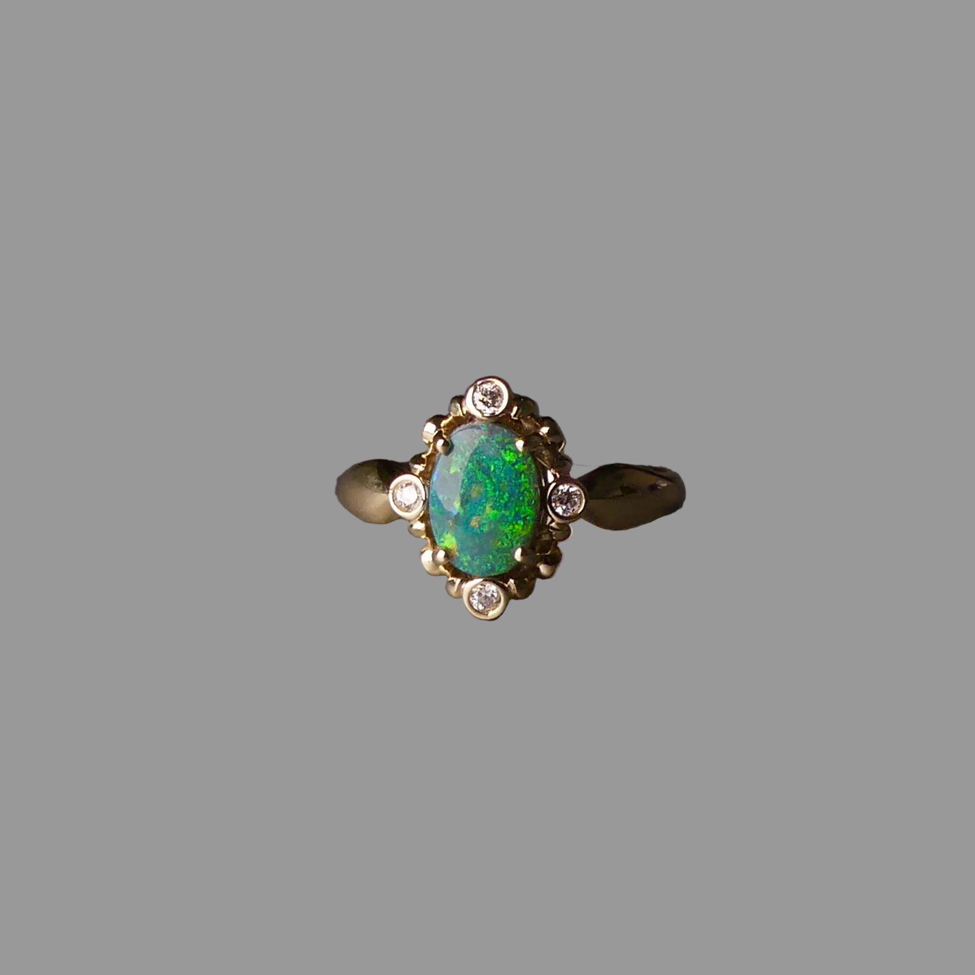 Gold ring with a green gemstone on a dark surface