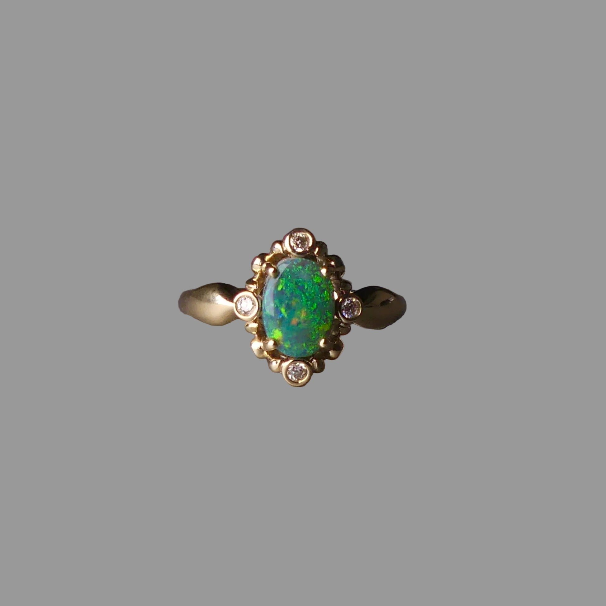 Gold ring with a green gemstone on a dark surface