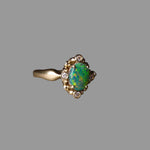 Gold ring with a green gemstone on a dark surface