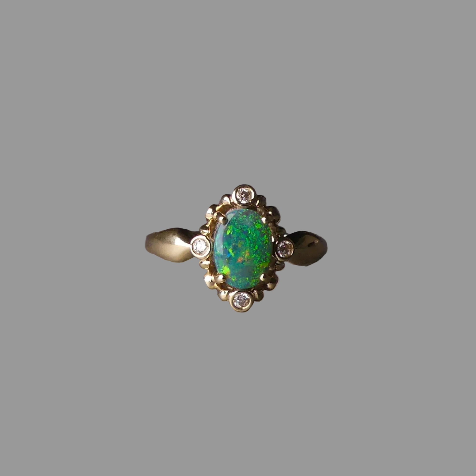 Gold ring with a green opal stone on a dark background