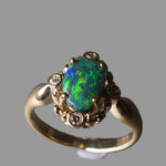 Gold ring with a green opal stone on a gray background