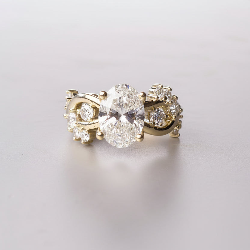 Gold ring with a large central diamond and smaller diamonds on the sides on a gray surface.