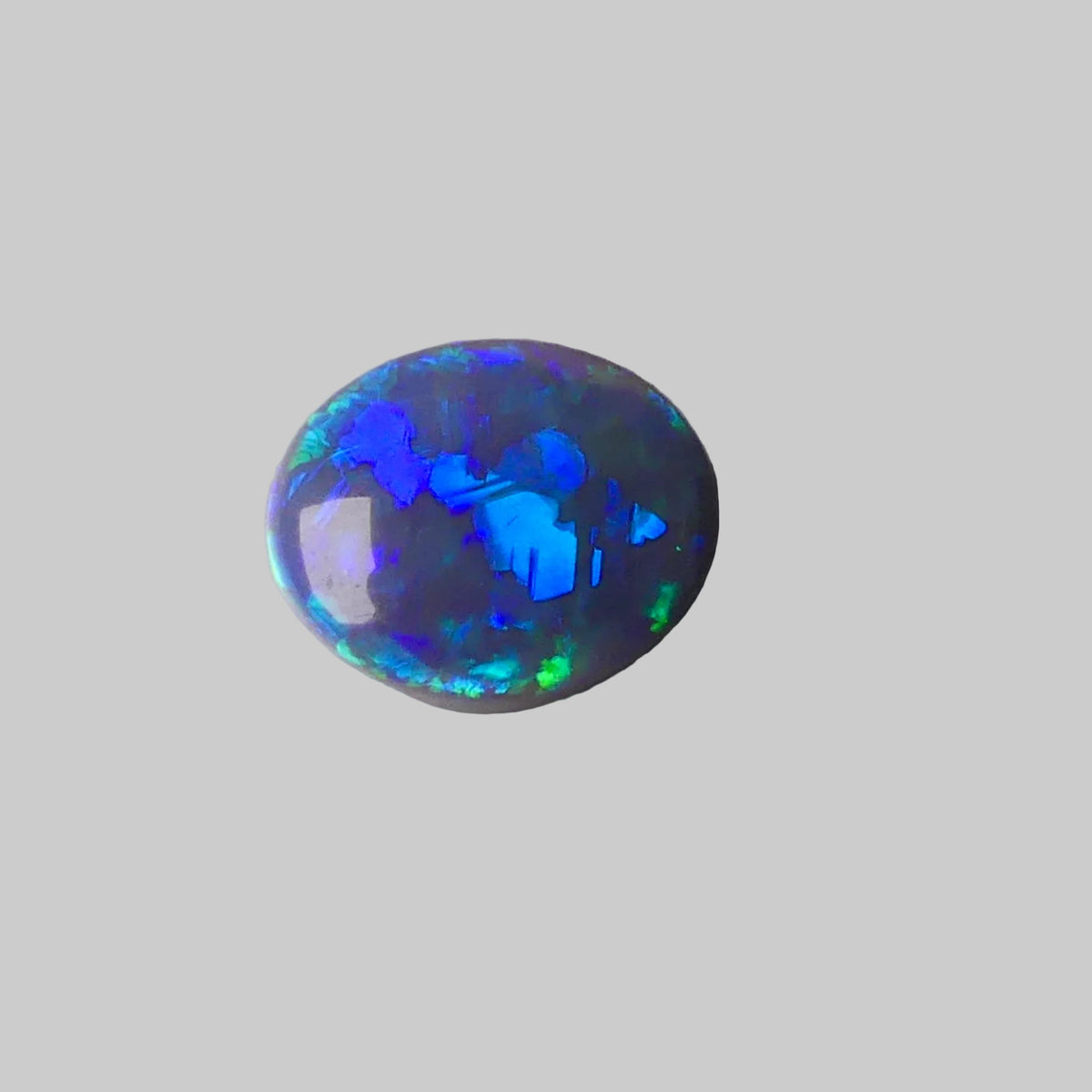 Opal stone with blue and green fluorescence on a gray background