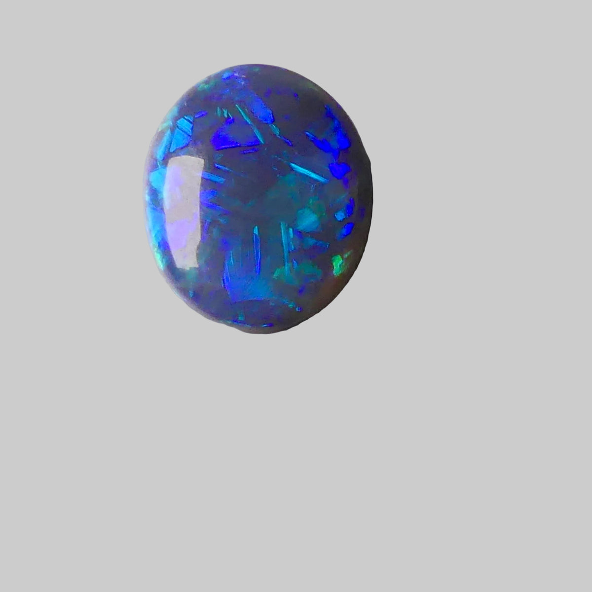 Opal stone with multicolored play of light on a gray background