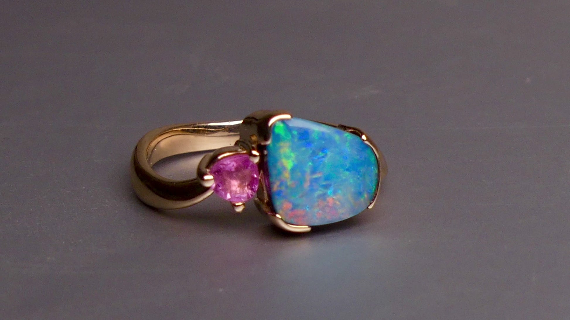 Indulge in luxury with our Elegant 9k Gold Australian Boulder Opal Ring. This opulent piece displays a mesmerizing array of colors, making it a true statement of elegance. Handcrafted with the finest materials, this ring exudes sophistication and exclusivity. Elevate your style and add a touch of opulence to any outfit.

Opal- 2ct Australian Boulder Opal

Origin- Queensland Australia

Setting- 9k Gold Bezel Set

Accent Stone- Pink Tourmaline

Size- 7 1/2
