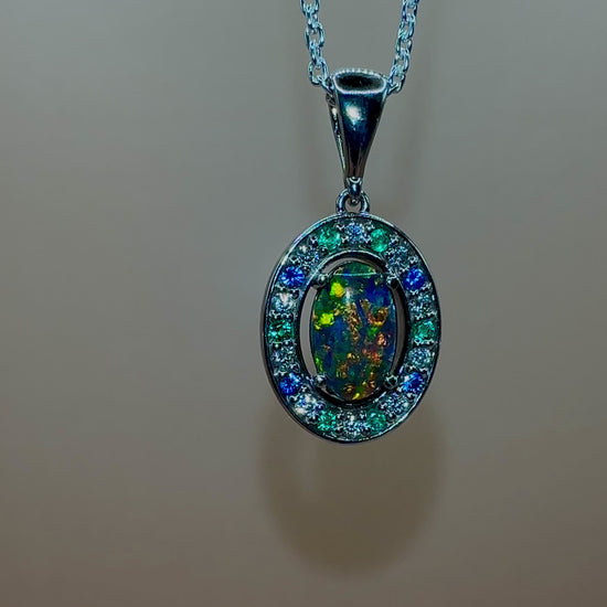 Lightning Ridge Australian black opal with strong, highly prized colors of reds, orange, and yellows is undoubtedly a remarkable gemstone. Expertly crafted from 18k white gold, this pendant showcases the mesmerizing beauty of an Australian black opal, surrounded by sparkling diamonds, emeralds, and sapphires. Exquisite in design and quality, this pendant is a luxurious addition to any jewelry collection. Elevate your style with this stunning piece.

Opal Weight- 1.1ct

Body Tone- N1 Australian Black