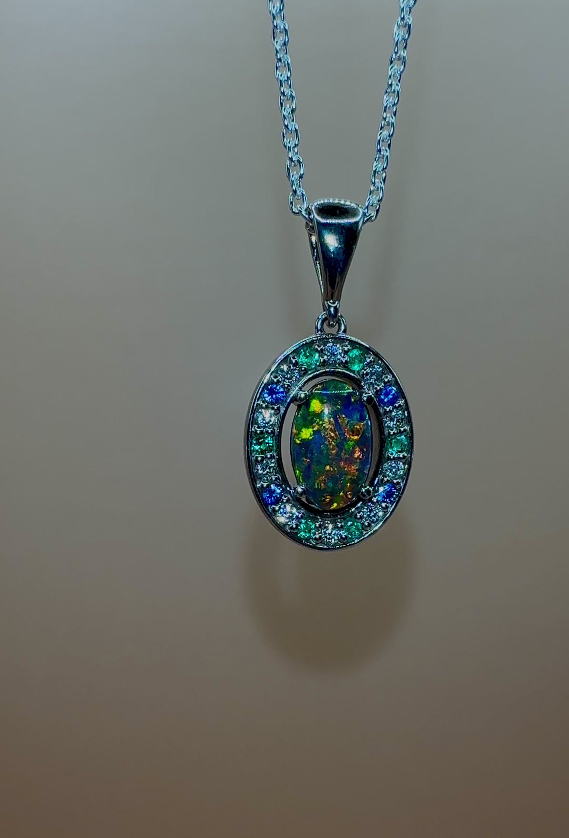 Lightning Ridge Australian black opal with strong, highly prized colors of reds, orange, and yellows is undoubtedly a remarkable gemstone. Expertly crafted from 18k white gold, this pendant showcases the mesmerizing beauty of an Australian black opal, surrounded by sparkling diamonds, emeralds, and sapphires. Exquisite in design and quality, this pendant is a luxurious addition to any jewelry collection. Elevate your style with this stunning piece.

Opal Weight- 1.1ct

Body Tone- N1 Australian Black