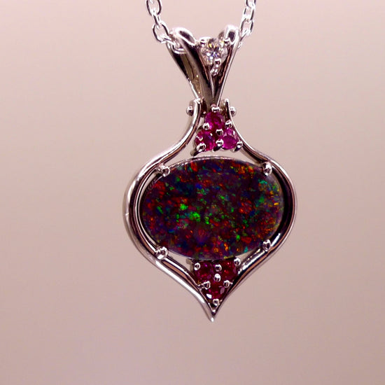 This stunning 18k white gold pendant features a rare and captivating Australian black opal accented with a brilliant center diamond and stunning rubies. Elevate your look with this breathtaking piece and indulge in the unique beauty and elegance of this precious gemstone.

Opal Weight- 1.6ct Australian Black Opal

Opal Origin- Lightning Ridge Australia

Setting- Rhodium Plated 18k White Gold

Accent Stones- Center Diamond, Rubies

Chain- 18k White Gold 45cm in length
